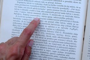 Kniha o bylinkách, text o šalvii a prst, ktorý ukazuje na konkrétny text