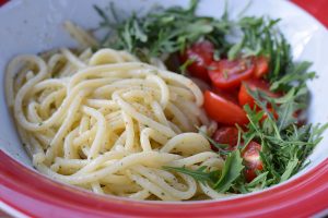 Špagety so šalviovým maslom, paradajkami a rukolou v tanieri