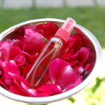 Ružová voda vo flakóne v miske s ružovými lupeňmi