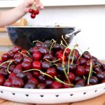 Čerešne v plytkej miske, detská ruka v pozadí