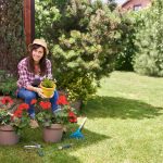 Bruneta v záhrade s muškátmi v kvetináčoch