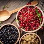 Čierne, červené a biele ríbezle v miskách na drevenom stole