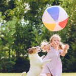 Dievčatko a pes hrajúci sa s loptou v záhrade