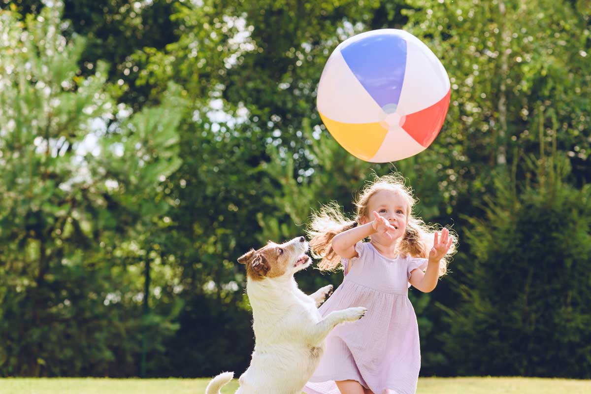 Dievčatko a pes hrajúci sa s loptou v záhrade
