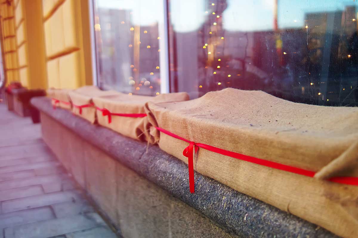 Kvetináče na parapete obalené jutovinou a červenou mašľou