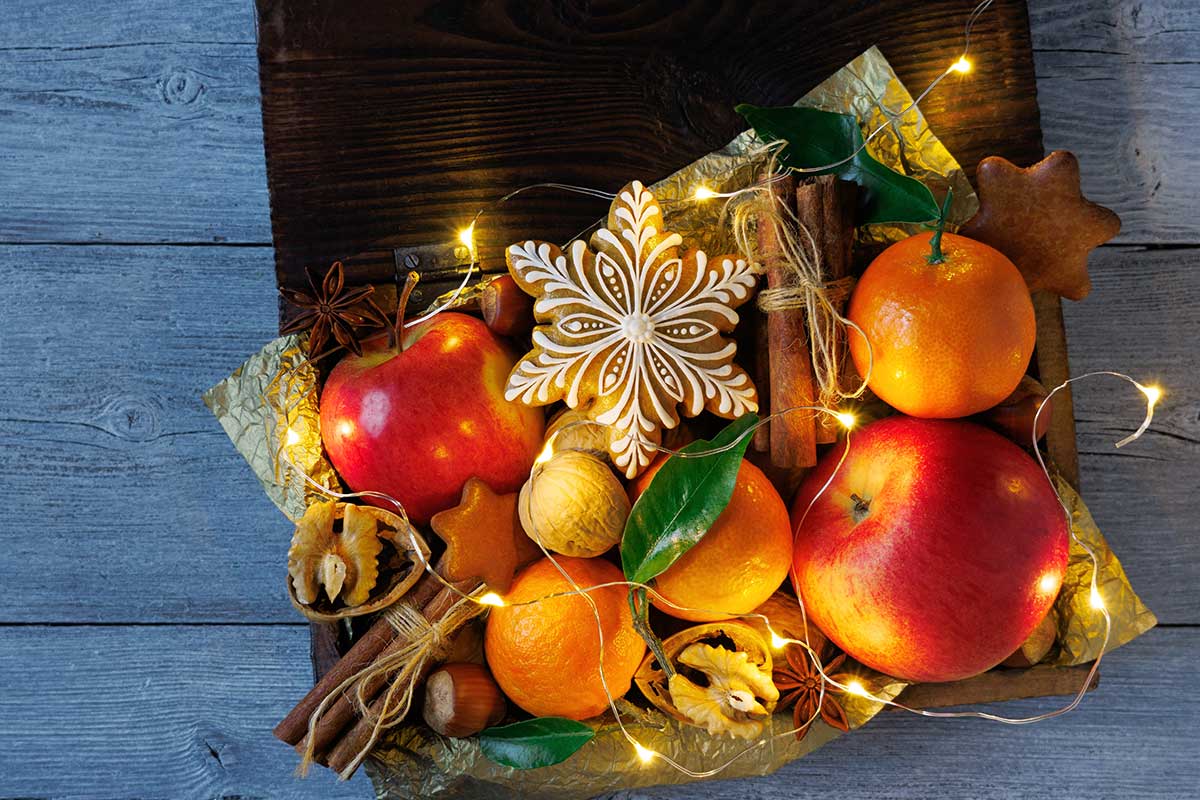 Mandarínky spolu s jablkami, orechmi a koreninami vo vianočnom aranžmáne