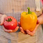 Záhradkárka porovnáva paradajku a papriku